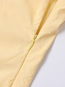 Close-up of high-quality invisible zipper on a yellow dress with fine vertical texture