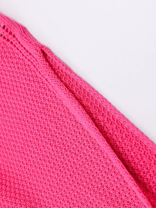 Détail macro du motif en crochet ajouré rose vif sur une robe de plage en maille