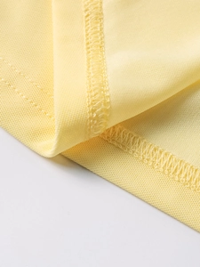 Détail macro des coutures de qualité et de la texture fine du tissu en maille jaune