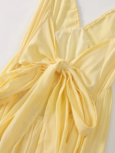 Detail of light yellow backless dress featuring a deep V-cut and stylish central tie knot