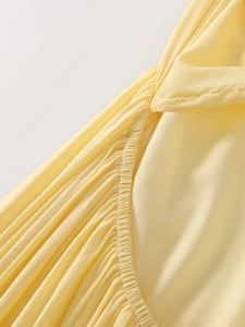 Close-up of gathered fabric texture and fine stitching on the pale yellow halter dress