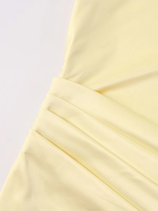 Detail of elegant waist pleats on a light yellow satin one-shoulder dress