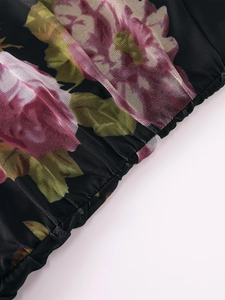 Detail shot of mesh fabric with rose prints and pleated stitching on a black dress