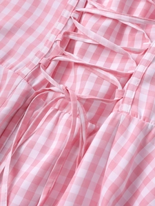 Close-up of pink and white gingham dress featuring lace-up criss-cross drawstring detail