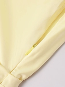 Close-up of the invisible zipper detail on a pale yellow satin one-shoulder dress