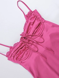 Dettaglio dell'abito in raso rosa acceso con pizzo delicato e design con coulisse frontale