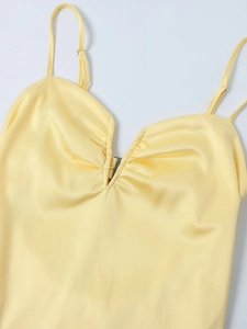 Detail des hellgelben Satin-Kleids mit tiefem V-Ausschnitt und kleiner Metallschnalle