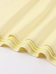 Detailed close-up of double-needle stitching and texture on a yellow satin dress hem