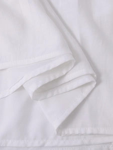 Detailed view of white stretchy fabric with neat stitching and layered pleats on a maxi dress