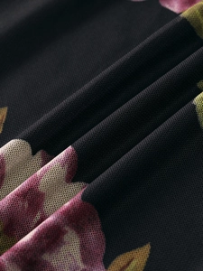 Close-up of floral mesh fabric with pink and yellow prints on black semi-transparent mesh
