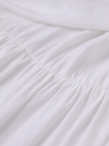 Macro detail of white four-way stretch fabric showing elegant gathered pleats and texture