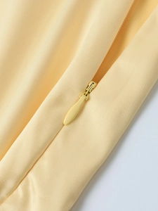 Detailaufnahme eines nahtlosen Reißverschlusses auf elegantem hellgelbem Satinstoff