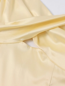 Detailed view of the knotted cutout and silky cream satin fabric on a V-neck midi dress