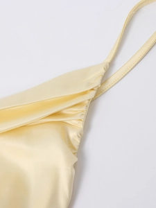 Close-up of elegant pale yellow satin dress featuring delicate straps and pleated chest detail