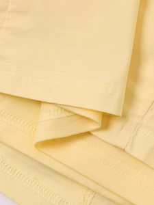 Vue macro détaillée du tissu jaune clair avec coutures doubles et ourlets professionnels