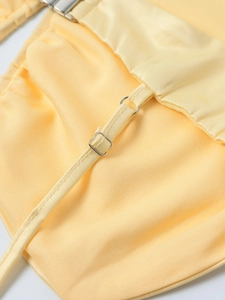 Detail der verstellbaren dünnen Träger und Metallschnalle am gelben Satin-Kleid