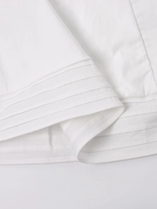 Detailed view of the horizontal decorative pin-tuck pleats on white cotton dress fabric