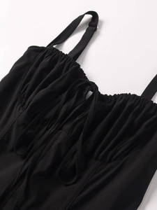 Detail of ruched black dress with adjustable spaghetti straps and center drawstring tie
