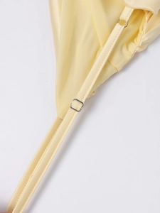 Detail of adjustable silver metal buckles on bright yellow satin dress straps