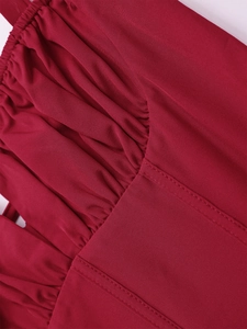 Close-up of red ruched fabric detail with double stitching on the fishbone dress