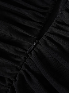 Detail shot of a concealed teardrop zipper on black ruched mesh fabric dress