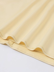 Close-up of light yellow satin dress hem showing smooth silk texture and fine stitching