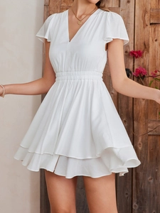 Detail of elegant white V-neck dress featuring layered ruffle skirt and butterfly sleeves
