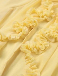 Close-up of sheer mesh fabric with delicate lettuce edge ruffles and pleated details