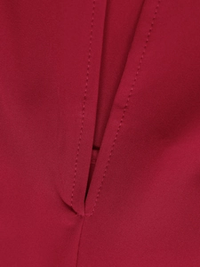 Detailed close-up of vertical slit with double stitching on deep red floral dress fabric