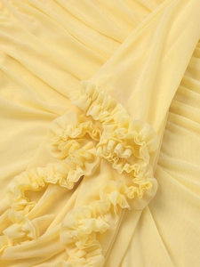 Detailed close-up of light yellow mesh fabric with layered ruffle and pleat textures