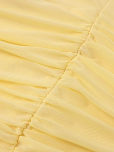 Macro detail of light yellow mesh fabric showing fine texture and gathered ruffle seams