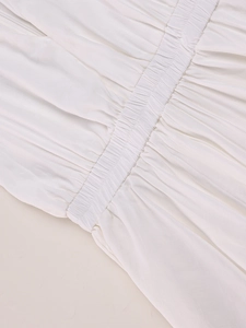 Detail of white dress with elastic smocked waist and vertical striped fabric texture