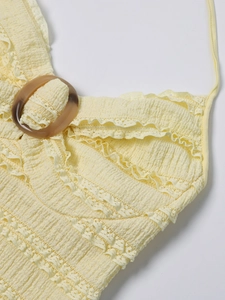 Detail of light yellow textured dress featuring a resin ring and delicate lace edges