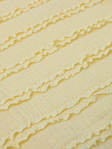 Macro detail of 3D textured lace embroidery on a light yellow backless maxi dress