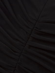 Macro view of the ruched black mesh fabric detailing the elegant gathered dress layers