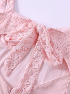 Détail de la robe en dentelle rose avec motif floral en résille et grand nœud décoratif