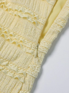 Detail view of the pale yellow dress with layered lace texture and invisible zipper
