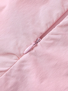Détail d'une fermeture éclair invisible sur une robe rose avec tissu à micro-texture