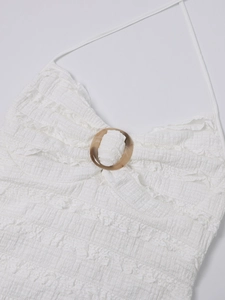 Close-up of white halter neck dress with seersucker texture and tortoiseshell ring detail