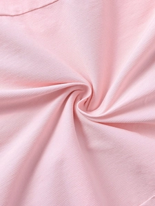 Gros plan sur le tissu gaufré rose clair montrant la texture délicate et le drapé