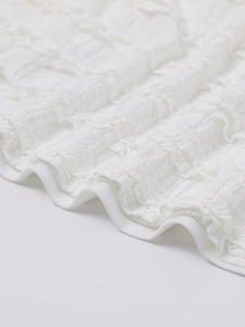 Detail of white popcorn fabric texture with 3D puckered effect on a halter dress