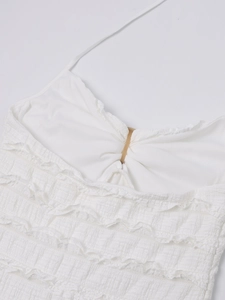 Detail view of white halter dress with textured fabric ruffles and ring connector