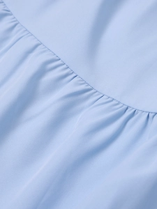Détail d'une robe bleu clair à volants montrant le tissu tissé lisse de haute qualité