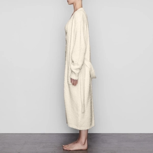 Detail of plush ivory fleece robe featuring side pockets and a soft tie belt waist