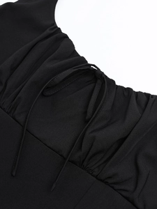 Detailaufnahme des schwarzen Kleides mit quadratischem Ausschnitt, Kordelzug und Raffung