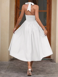 Detail view of the white backless halter dress featuring a large bow tie and smocked waist
