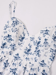 Détail de la robe à fleurs avec col en V, fines bretelles et motifs floraux bleus élégants