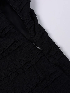 Detailed close-up of black pleated textured fabric with a hidden zipper closure