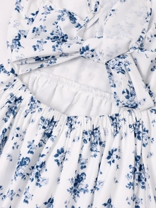 Détail de bretelles croisées et dos élastique avec imprimé floral bleu sur robe blanche