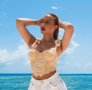 Detail of light beige corset top with shoulder bows and fishbone structure by the sea